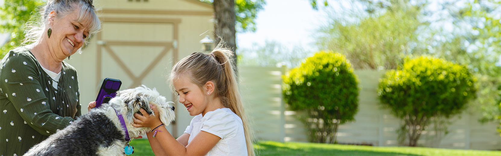 Lady and small child smile while petting a dog.